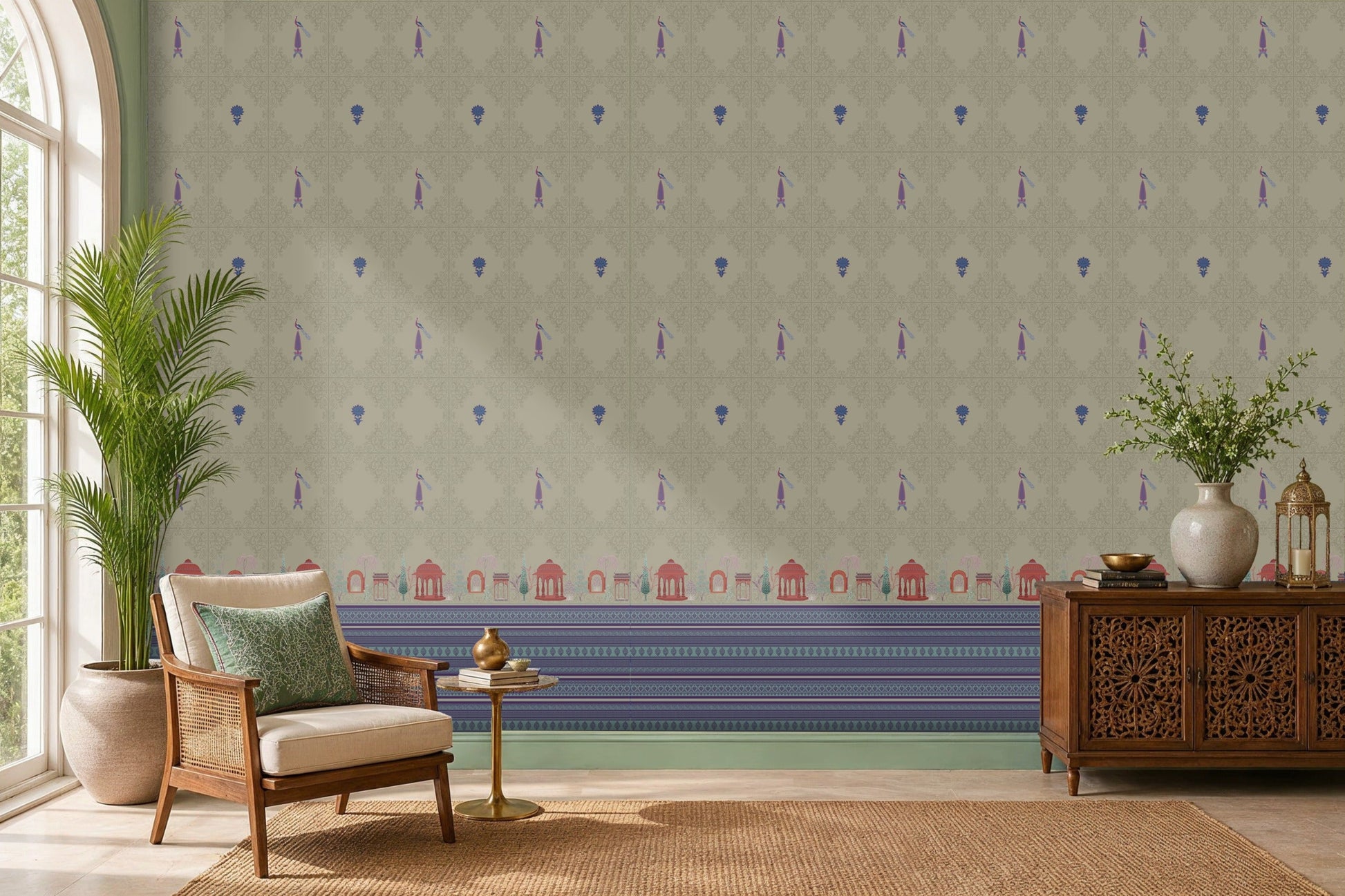 Royal Garden Heritage Wallpaper in Pistachio Green featuring intricate floral motifs, elegant peacock-inspired details, and decorative Mughal garden architecture borders in royal blue and rani pink, styled in a bright living room with cane furniture, carved wooden cabinetry, indoor plants, and natural woven textures.