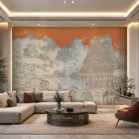 Contemporary living room featuring a large mural wallpaper in soft gray tones depicting misty mountains, traditional architecture, and an ornate South Indian temple against a warm sunset-orange background. The space includes a cream sectional sofa with neutral and rust-colored cushions, a round dark wood coffee table, and a cognac accent chair. Recessed lighting, natural textures, and minimalist furnishings create a serene, sophisticated atmosphere that blends modern design with Asian-inspired artistic elem