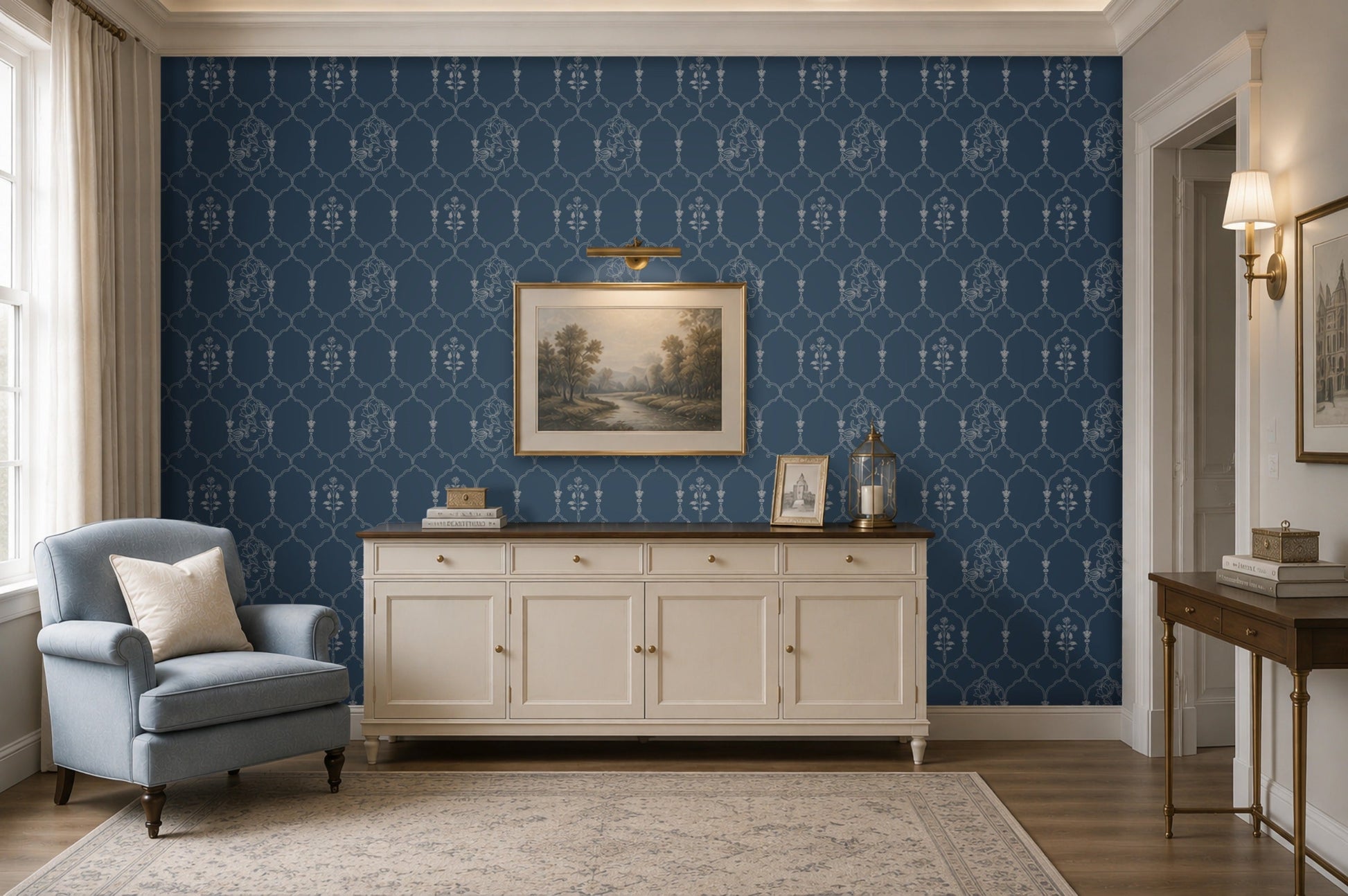 Deep heritage blue wallpaper featuring an intricate Pichwai-inspired trellis pattern with delicate floral motifs and traditional cow illustrations, styled behind a cream sideboard with framed landscape art and brass décor accents in an elegant living room.