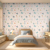 Little Mariners kids wallpaper in a soft pastel color way featuring playful whales, sailboats, lighthouses, turtles, submarines, and sea creatures, styled in a bright children's bedroom with light blue bedding and nautical-inspired décor.