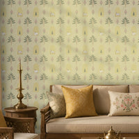 Soft sage Indian heritage wallpaper featuring hand-drawn trees, arches, florals and cow motifs, styled in a warm traditional living room with wooden furniture and brass décor.