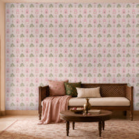 Pink floral wallpaper featuring repeating hand-drawn arches, stylized trees, and delicate botanical motifs, creating a soft Indian-inspired pattern in a warm, elegant living room with wooden furniture and blush-toned décor.
