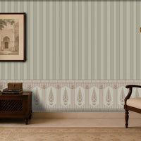 Elegant vintage-inspired sitting room with sage green vertically striped wallpaper, ornate patterned wainscoting, a framed architectural print, brass wall sconces, a dark wooden sideboard with decorative objects, and a carved wooden armchair with a beige cushion and patterned pillow.
