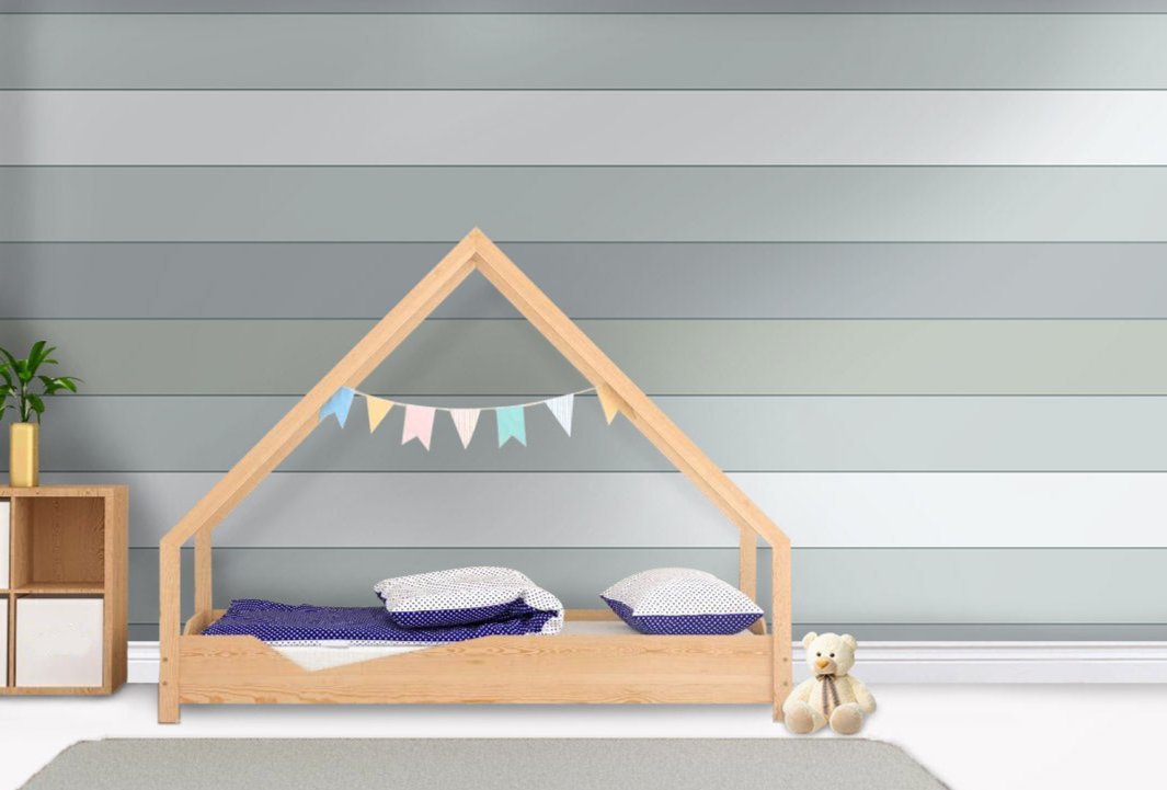 A playful child's bedroom features a modern planked wallpaper in a hit grey theme.
The clean design showcases wide, horizontal shiplap bands in soft shades of grey and muted teal.
In front, a minimalist light-wood house bed frame sits centered on the floor with blue bedding.
The bright, contemporary space is beautifully completed by a small teddy bear sitting on the right.