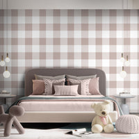 A cozy bedroom features a soft pastel checks wallpaper in a pastel silver theme.
The delicate design displays a clean grid pattern with intersecting muted pink-grey and white blocks.
In front, a neatly made bed with dusty pink pillows and blankets is centered in the space.
The sweet, modern interior setup is nicely completed by a plush teddy bear sitting on the floor.