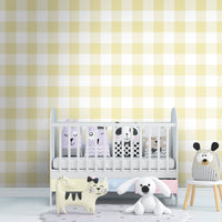 A cozy bedroom features a soft gingham check wallpaper in pastel silver.
The design displays a large grid pattern with alternating dusty pink-grey and white blocks.
In front, a neatly made bed with pink pillows and sheets is centered in the space.
The modern kids' room setup is nicely completed by a plush teddy bear sitting on the rug.