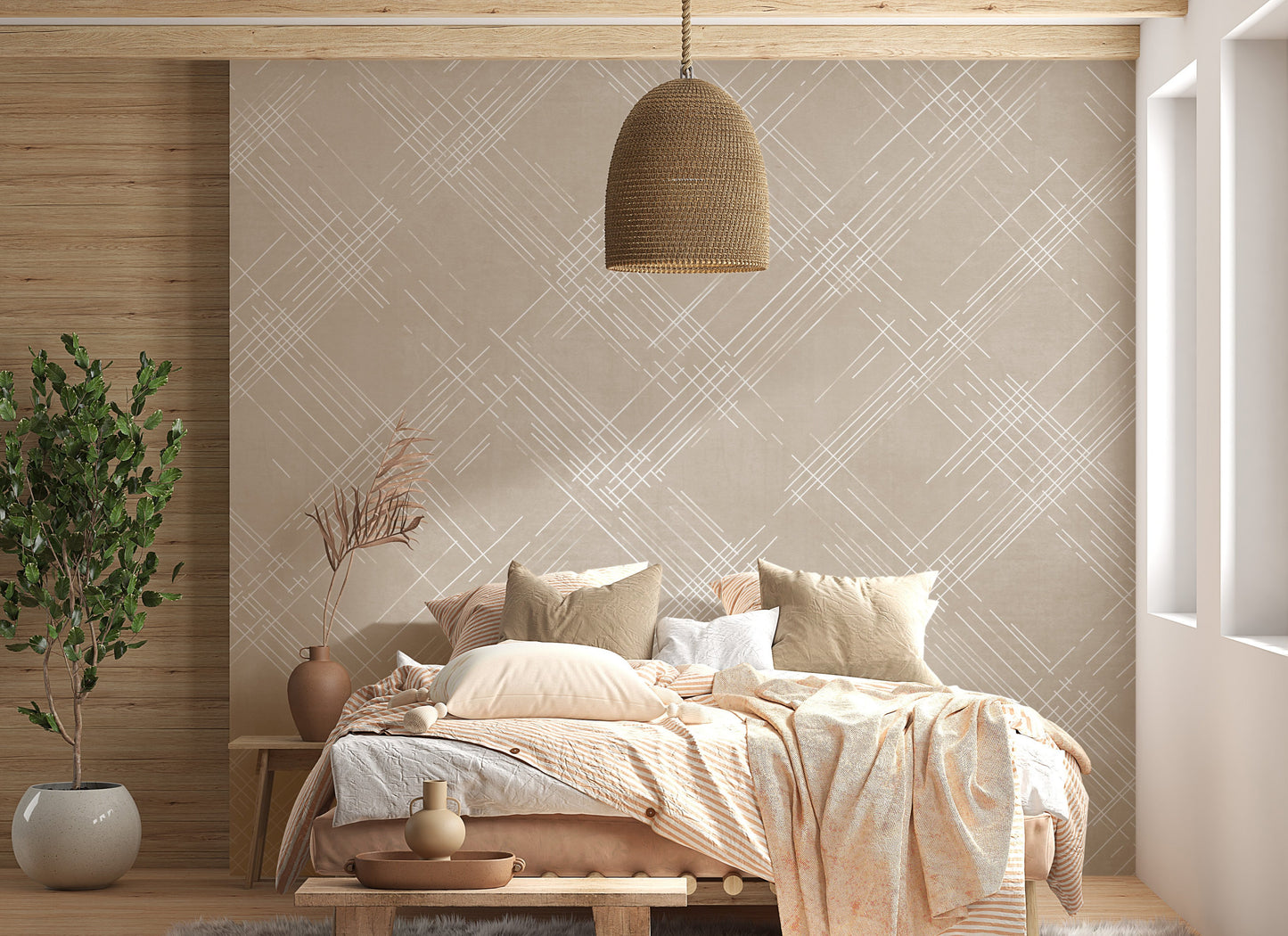 A bright living room features a textured crosshatch wallpaper in a warm beige theme.
The fabric-look pattern displays intersecting white sketch lines angled dynamically over a sandy beige backdrop.
In front, a cozy white sofa with colourful textured pillows sits next to a light wood lounge chair.
The sunny, welcoming interior space is beautifully completed by a tall, leafy green potted plant.
