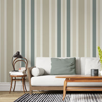 A minimal living room features a textured striped wallpaper in a whisper sand theme.
The fabric-textured design shows clean vertical lines in muted sage green, beige, and cream.
In front, a comfortable white sofa with grey throw pillows is centered in the space.
The calm interior setup is beautifully completed by a leafy green potted plant on the right.