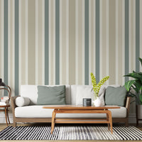 A minimal living room features a textured striped wallpaper in a whisper sand theme.
The fabric-textured design shows clean vertical lines in muted sage green, beige, and cream.
In front, a comfortable white sofa with grey throw pillows is centered in the space.
The calm interior setup is beautifully completed by a leafy green potted plant on the right.
