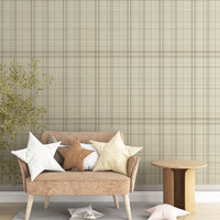 A modern bedroom features a textured plaid wallpaper in sahara blush and cream tones.
The fabric-look design displays a detailed grid pattern with intersecting soft pink, orange, and tan lines.
In front, a fully dressed bed with cream linens sits next to a classic pink wingback accent chair.
The elegant, cozy space is completed by a small wooden nightstand and a soft pink area rug.