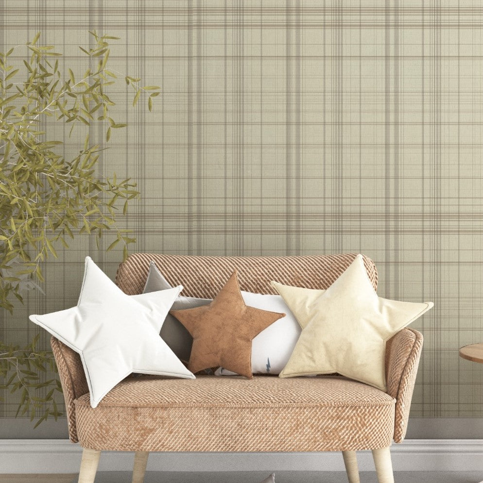 A modern bedroom features a textured plaid wallpaper in sahara blush and cream tones.
The fabric-look design displays a detailed grid pattern with intersecting soft pink, orange, and tan lines.
In front, a fully dressed bed with cream linens sits next to a classic pink wingback accent chair.
The elegant, cozy space is completed by a small wooden nightstand and a soft pink area rug.