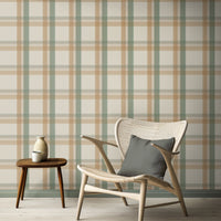 A calm, modern interior space features a classic plaid wallpaper in cream and beige tones.
The detailed fabric-look design displays a structured grid pattern with intersecting tan and sage green lines.
In front, an elegant light wood lounge chair with a dark grey pillow is placed to the right.
The simple minimalist room setting is completed by a small three-legged wooden side table on the left.