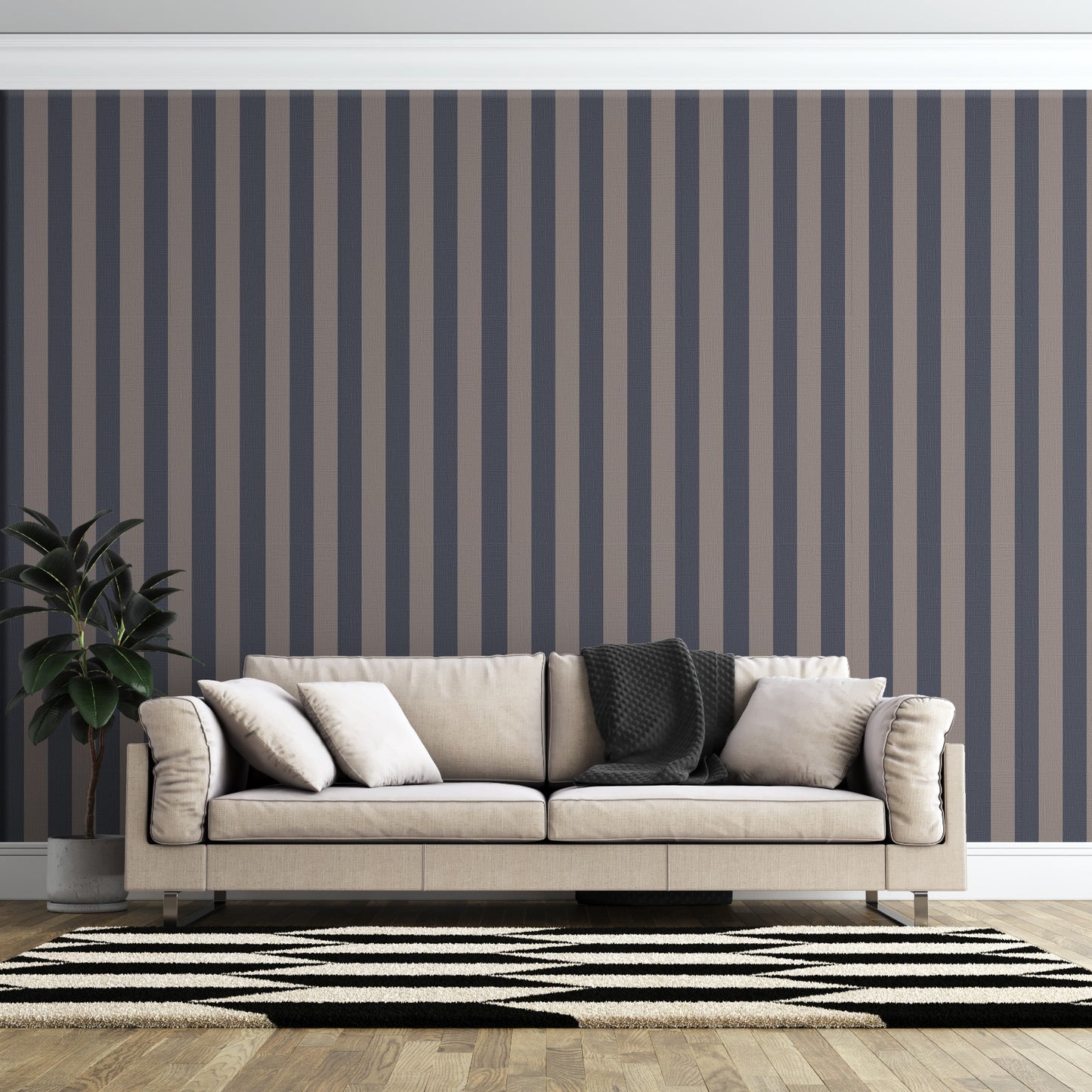 A modern living room features a dark navy blue and muted grey-brown striped wallpaper.
The design showcases clean, evenly spaced vertical stripes filling the entire back wall.
In front, a beige fabric sofa with decorative pillows rests on a chevron pattern rug.
The contemporary, stylish space is finished with a large potted green plant on the left.
