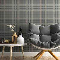 A classic interior study space features a traditional plaid wallpaper in sage green and cream tones.
The detailed textile-look design showcases an intricate grid pattern of intersecting dark green and beige lines.
In front, a large dark wood desk with three drawers is paired with a comfortable taupe office chair.
The elegant, professional setting is completed by a warm desk lamp and a vibrant green potted plant.