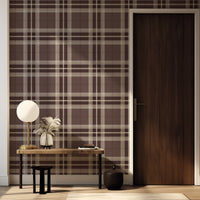 A modern dining room setup features a classic tartan plaid wallpaper in soft grey and white tones.
The textured design displays a clean grid pattern with intersecting grey lines across the wall.
In front, a dark wood dining table is paired with matching chairs with grey upholstered cushions.
The elegant room layout is beautifully completed by an open window view showing a touch of greenery.