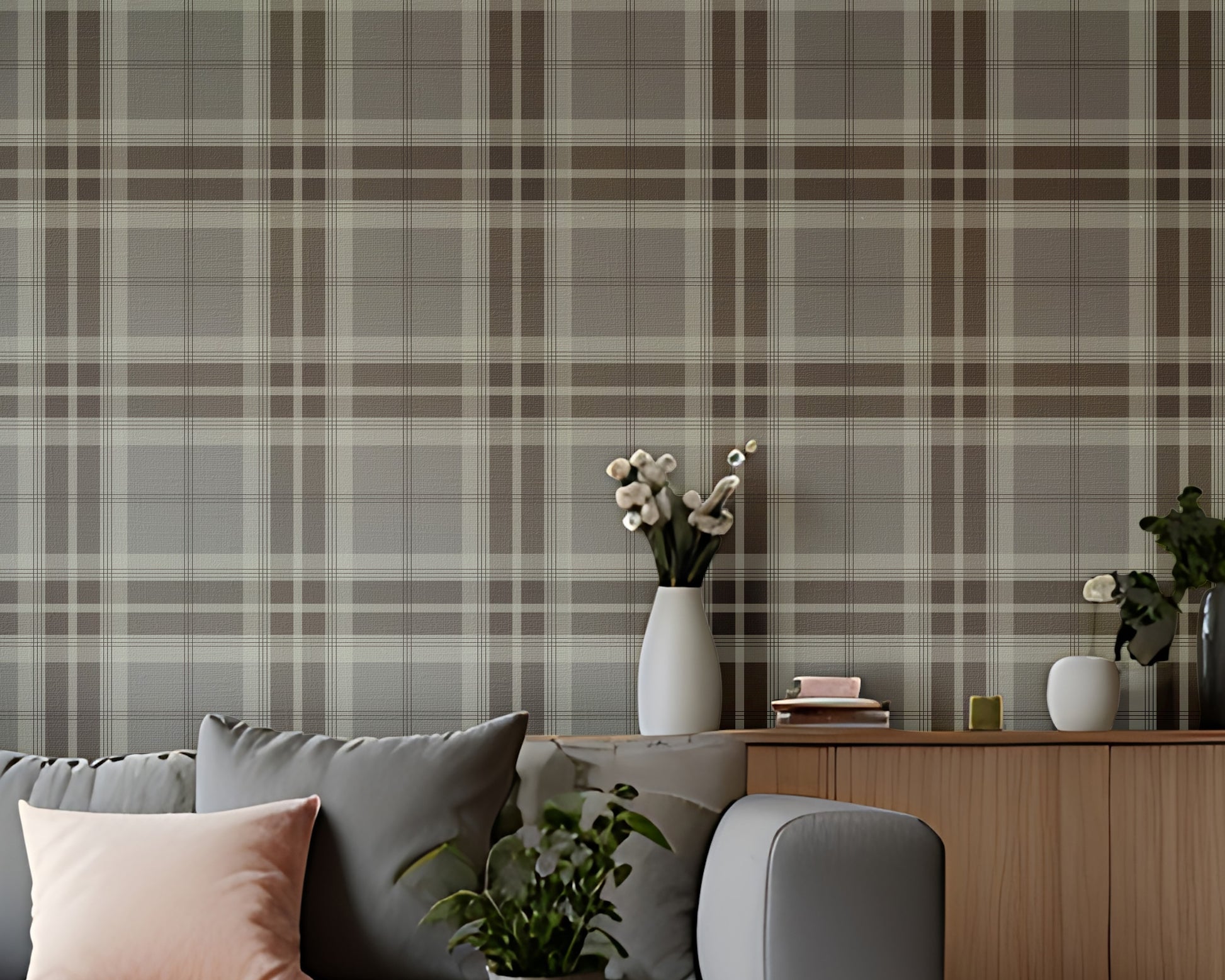 A modern entryway hallway features a classic truffle tartan plaid wallpaper in rich chocolate brown and cream tones.
The textured fabric-look design displays a bold grid pattern with intersecting brown and off-white bands.
In front, a minimalist light wooden console table stands next to a tall, dark wood interior door.
The warm, inviting space is completed by a round white globe lamp and a small decorative stool.