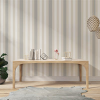 A modern living room features a textured striped wallpaper in a subtle sandstone theme.
The fabric-textured design shows clean vertical lines in light grey, cream, and warm beige.
In front, a minimalist light wooden console table sits straight in the center of the space.
The bright, open interior layout is beautifully completed by a green potted plant on the left.
