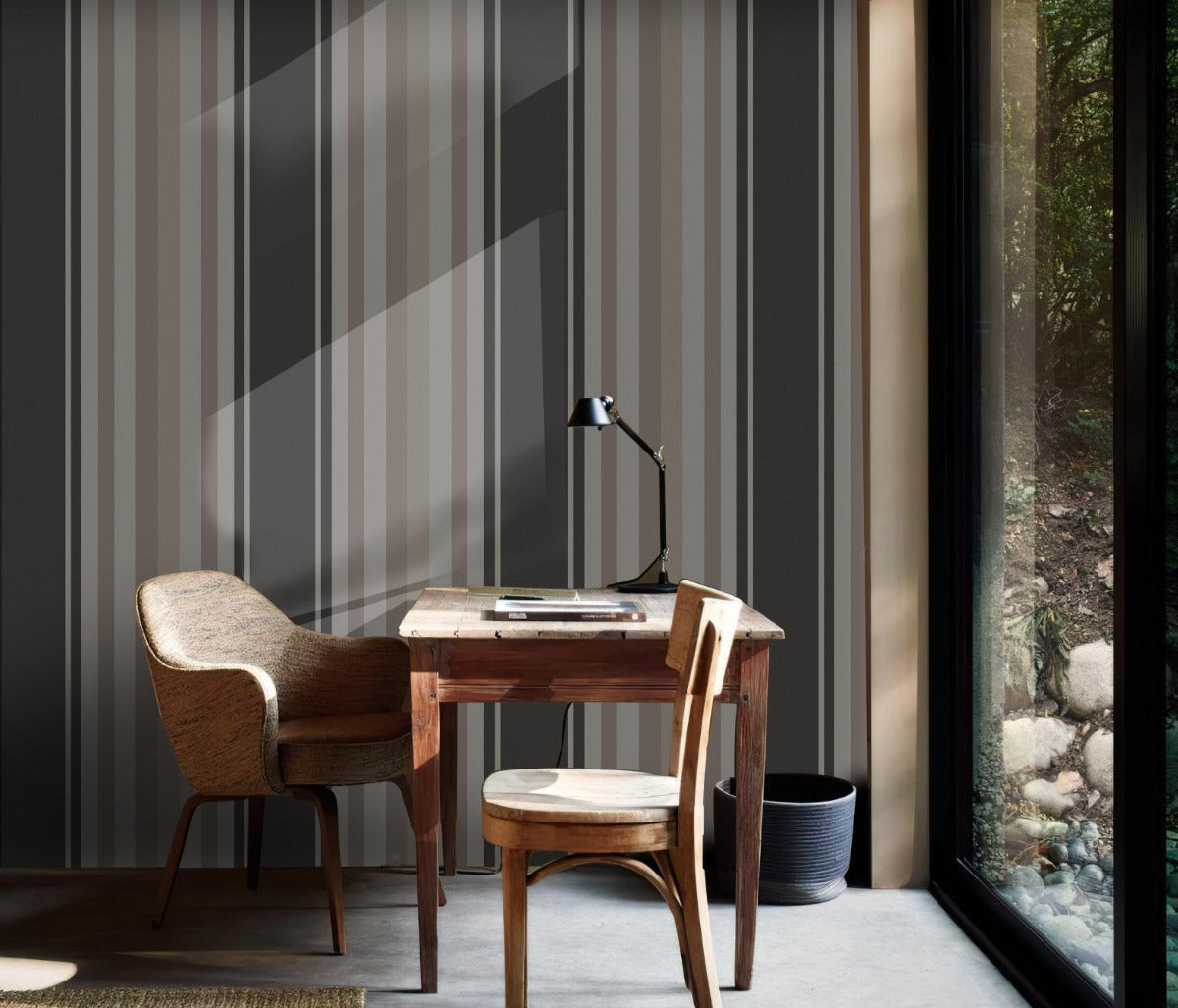 A moody room setup features a bold midnight timber charcoal and black striped wallpaper.
The detailed design shows alternating thick black vertical bands and dark grey patterned stripes.
In front, a rustic dark wood cabinet stands against the wall holding small decorative items.
The sophisticated interior setup is nicely finished with a minimalist black metal chair to the left.
