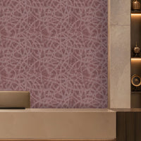 A refined contemporary reception area featuring a large curved-front desk in warm ivory stone and dark wood, with subtle integrated underlighting. The backdrop is a mauve-taupe textured feature wall with an intricate organic pattern and softly illuminated upper edge. Vertical dark-wood slats frame the left side, while marble-clad columns and illuminated display niches with sculptural décor frame the right. Warm architectural lighting, polished stone flooring, and restrained neutral tones create an elegant