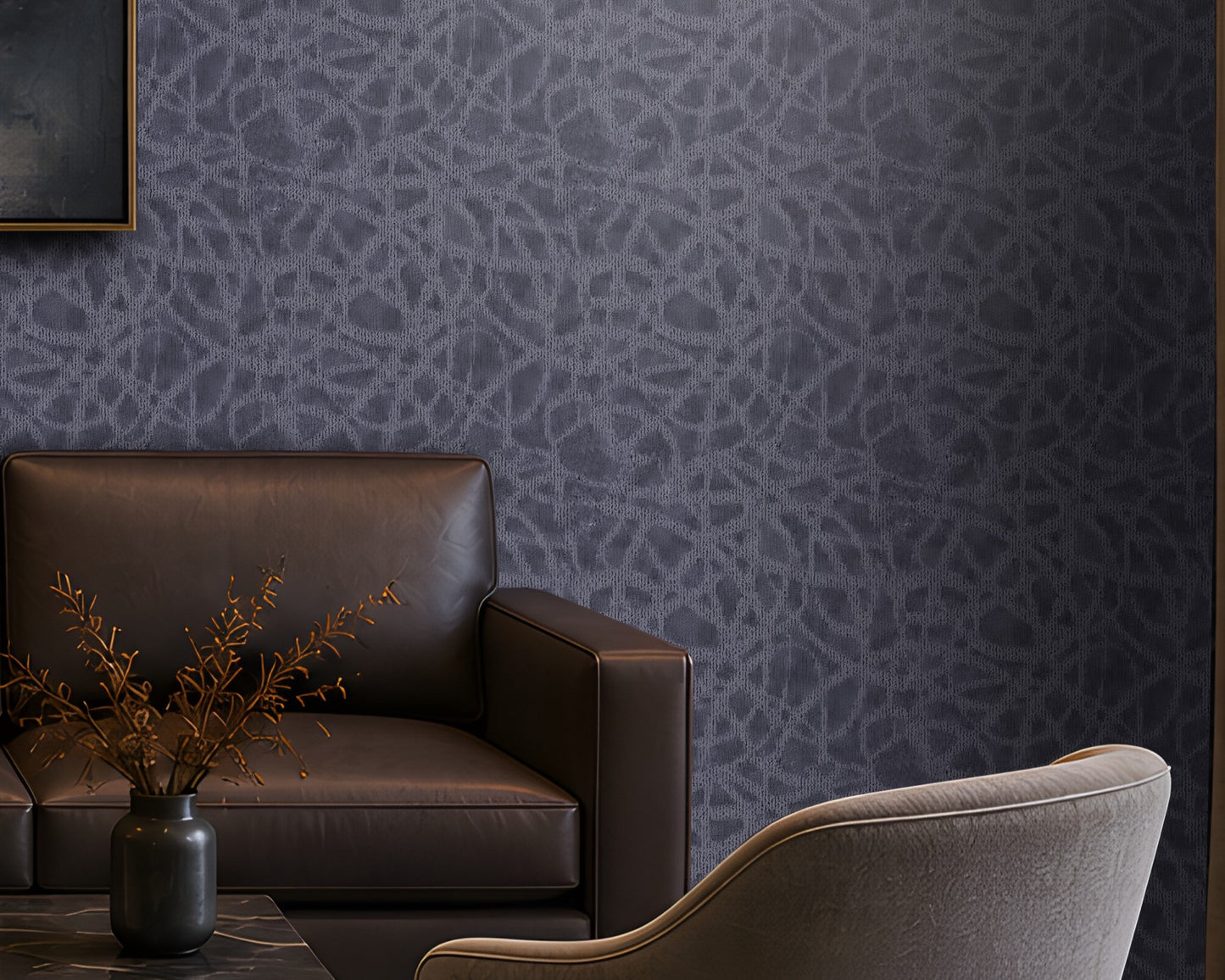 "Modern living room featuring a premium slate blue seamless texture wallpaper with an elegant organic abstract pattern that adds depth and visual interest to the walls. The sophisticated interior includes a dark brown leather sofa, two upholstered accent chairs, a black marble coffee table, warm brass table lamp, built-in wooden shelving with ambient lighting, abstract wall art, and floor-to-ceiling curtains. This luxurious textured wallpaper is ideal for contemporary