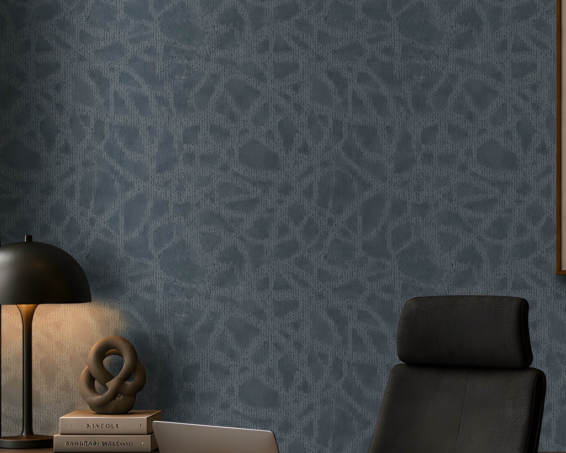 A modern, moody home office featuring a dark blue textured accent wall, warm walnut cabinetry and desk, black leather office chair, minimalist abstract artwork, integrated shelving with warm LED lighting, and abundant greenery. Natural light enters from the tall window on the left, complemented by warm recessed ceiling lights. The overall aesthetic is sophisticated, contemporary, and calm, with earthy materials and muted tones.
