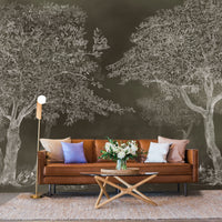 An architectural perspective of a sophisticated study featuring the Aranyam Dark Umber Mural as a full-scale feature wall behind a tan leather sofa. The mural’s dark, illustrative vista pairs elegantly with warm wooden furniture and gold accents, creating a moody and cultured interior sanctuary.