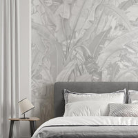 A high-resolution detail of the Banana Grove Dreams Grey Wallpaper, highlighting the delicate painterly textures and hand-painted veining of the tropical leaves. The image showcases the refined tonal transitions between smoky charcoal, misty grey, and soft ivory that define this nature-inspired mural.