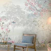 Close-up of Blossom Reverie ice blue floral landscape wallpaper featuring delicate pink cherry blossoms, botanical foliage, colorful wildflowers, and birds against a misty forest background.