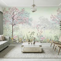 Modern living room featuring Blossom Reverie willow green floral landscape wallpaper with pink cherry blossom trees, birds, and misty forest scenery, complemented by a sage green sofa, wooden cane chairs, and a white coffee table.