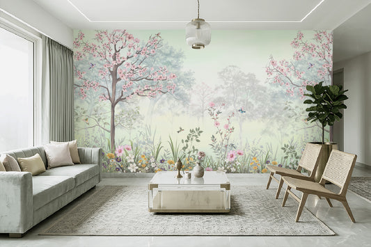 Modern living room featuring Blossom Reverie willow green floral landscape wallpaper with pink cherry blossom trees, birds, and misty forest scenery, complemented by a sage green sofa, wooden cane chairs, and a white coffee table.