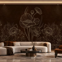 A modern living room featuring a large dark brown floral wall mural with white line-art poppy designs behind a curved cream sectional sofa, a round black coffee table, and a rust-orange accent chair.