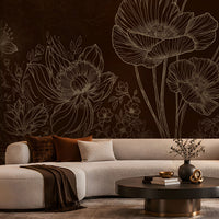 A modern living room featuring a large dark brown floral wall mural with white line-art poppy designs behind a curved cream sectional sofa, a round black coffee table, and a rust-orange accent chair.