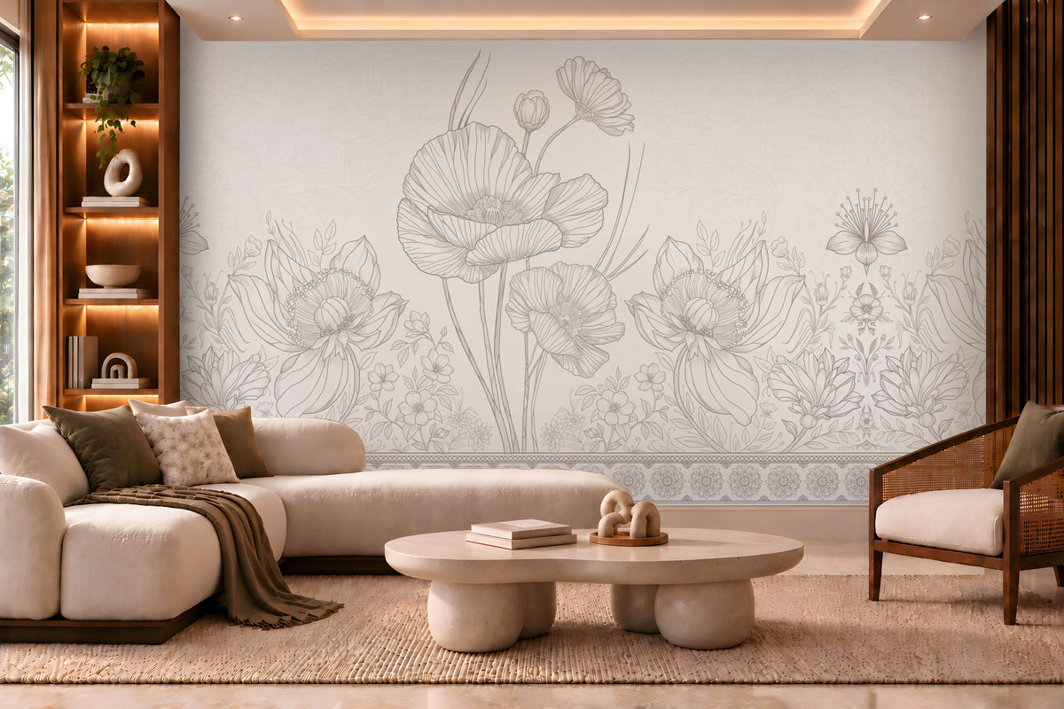 A modern living room featuring a large wall mural with delicate gray floral line art on a light beige background. The room is styled with a cream-colored sectional sofa, a round stone coffee table, a wooden armchair, and warm ambient lighting.