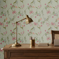 Sage green seamless floral wallpaper featuring an intricate repeating pattern of delicate pink, blush, and peach flowers intertwined with slender green botanical vines and leaves. The elegant floral motifs are arranged in a balanced continuous pattern, creating a soft, graceful, and sophisticated look. The muted pastel palette complements traditional Indian-inspired interiors while adding a fresh, serene, and luxurious character to the wall.
