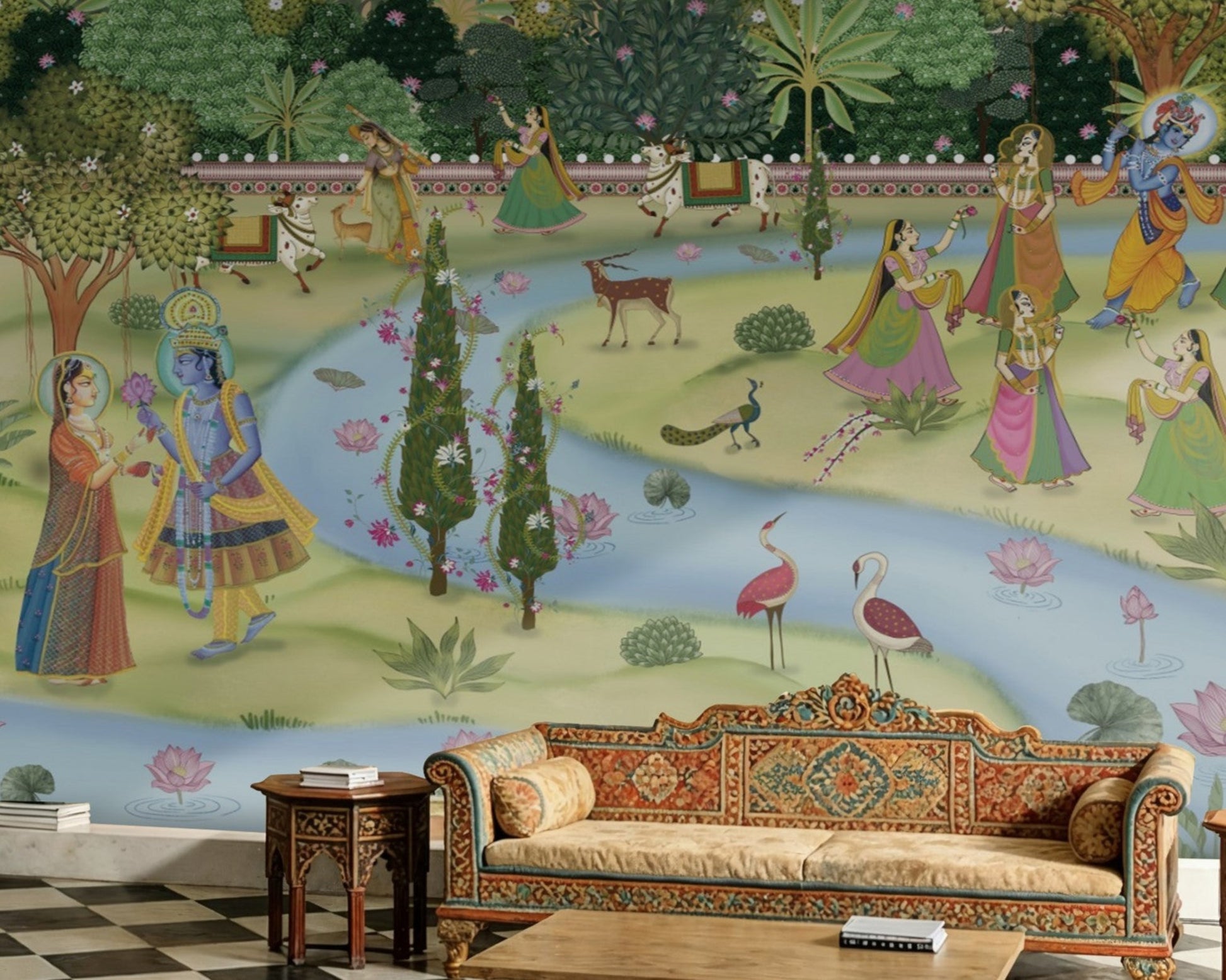A panoramic architectural view of a luxury Indian palace interior featuring a full-scale Pichwai Mural Wallpaper. The mural depicts Lord Krishna in a sacred garden setting, paired with an ornate carved archway, checkered marble flooring, and traditional Rajasthani furniture.