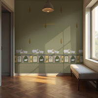 Green-toned interior room with patterned wallpaper featuring small animal motifs and a decorative border with plants and framed designs. A cushioned bench sits along the right wall beneath a window, while a hanging ceiling light is centered above. Sunlight enters through the window, casting soft shadows across the wall and wooden floor, with an open doorway visible on the left.