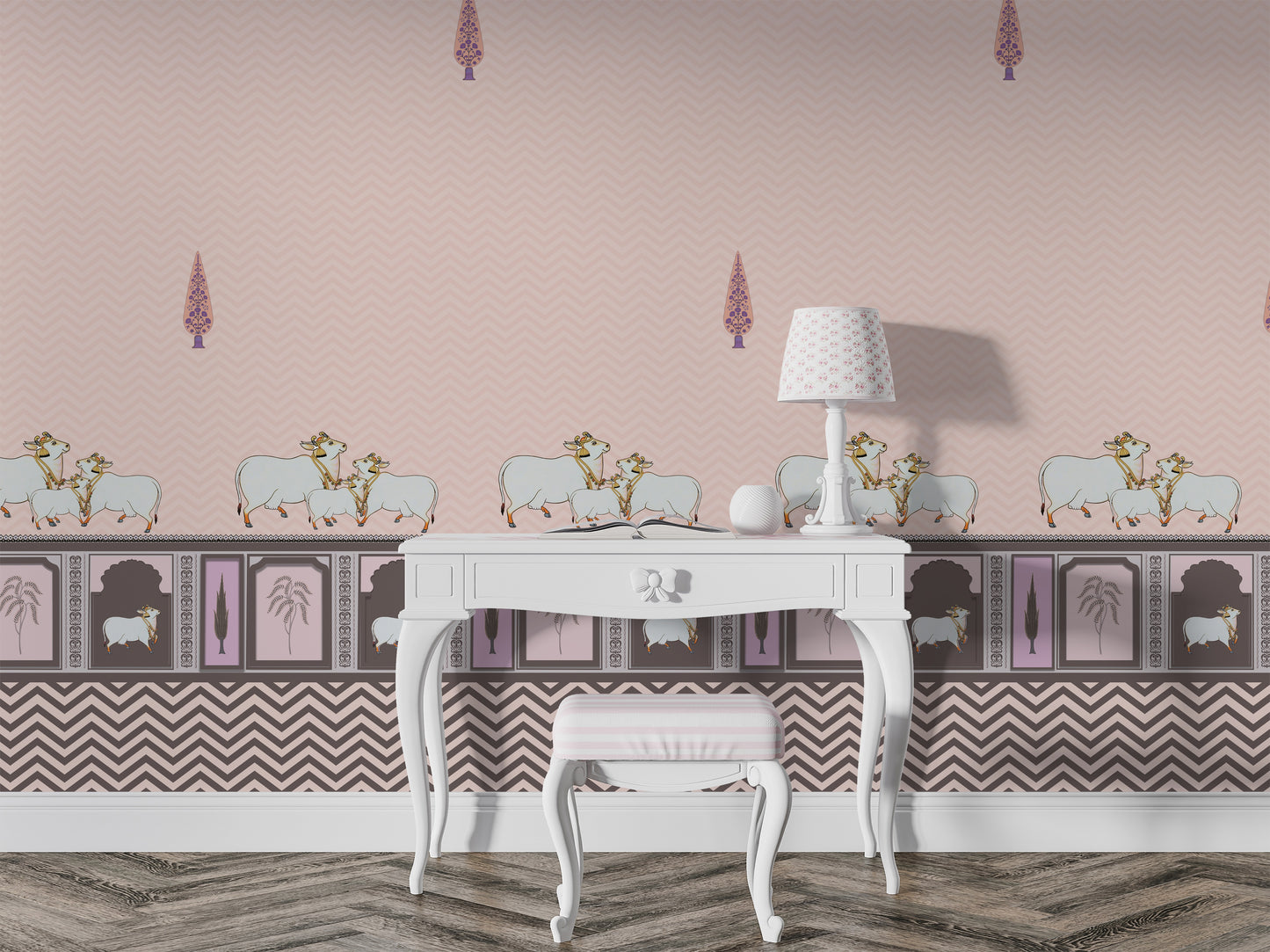 Light pink room with patterned wallpaper featuring small decorative motifs and sheep illustrations along a border. A white vintage-style desk with curved legs sits against the wall, paired with a small cushioned stool. On the desk is a white lamp with a patterned shade and a small decorative object. The floor has a textured, zigzag-patterned rug in neutral tones.