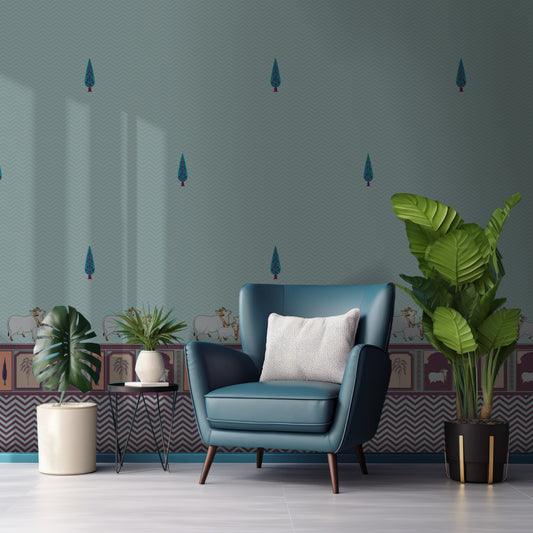 An elegantly decorated living room featuring a large accent wall with light blue wallpaper. The wallpaper is adorned with a pattern of small, stylized teal cypress trees and a decorative border along the bottom showing white cows and traditional arch motifs in purple and pink.