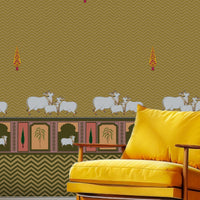 An architectural perspective of a high-ceilinged room featuring the Heritage Pichwai Wallpaper as a warm, inviting feature wall. The mural’s golden and earthy tones pair strikingly with traditional carved wooden furniture, neutral linen upholstery, and brass accents, creating a space that blends classical Indian heritage with a cozy, modern-rustic aesthetic.