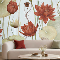 A large-scale lotus wallpaper mural featuring red and orange lotus flowers and green lily pads on a pale blue background, shown behind a modern beige sofa with decorative pillows in a styled living room setting.