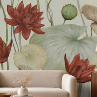 A large-scale botanical wall mural featuring red lotus flowers and pale green lotus leaves, shown in a styled living room setting behind a beige sofa with a wooden side table and lamp.