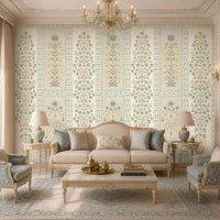 Elegant heritage-style living room featuring a light blue and muted sage green floral wallpaper with intricate botanical patterns and decorative panel detailing on a warm ivory background. The wallpaper complements a cream upholstered sofa, blue patterned accent chairs, an ornate beige and blue rug, and classic ivory furniture with gold accents, creating a luxurious and serene traditional Indian-inspired ambience.