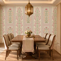 Elegant pastel floral wallpaper featuring delicate purple and peach flowers with soft sage-green vines on a light cream background, showcased in a luxurious Indian-style bedroom with ornate ivory furniture, blush pink accents, traditional arched windows, and warm chandelier lighting.
