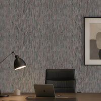 A styled home office scene featuring textured vertical wood-look wallpaper in gray and muted blue tones, a black desk lamp, a black leather office chair, a laptop on a wooden desk, and a framed abstract art print on the wall.