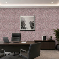 A modern office interior featuring textured pink wallpaper on the main wall, a dark wood conference table, black office chairs, a laptop, a framed black-and-white cityscape print, and a potted plant.