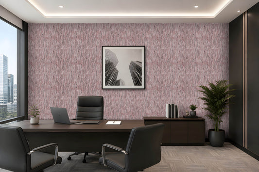 A modern office interior featuring textured pink wallpaper on the main wall, a dark wood conference table, black office chairs, a laptop, a framed black-and-white cityscape print, and a potted plant.