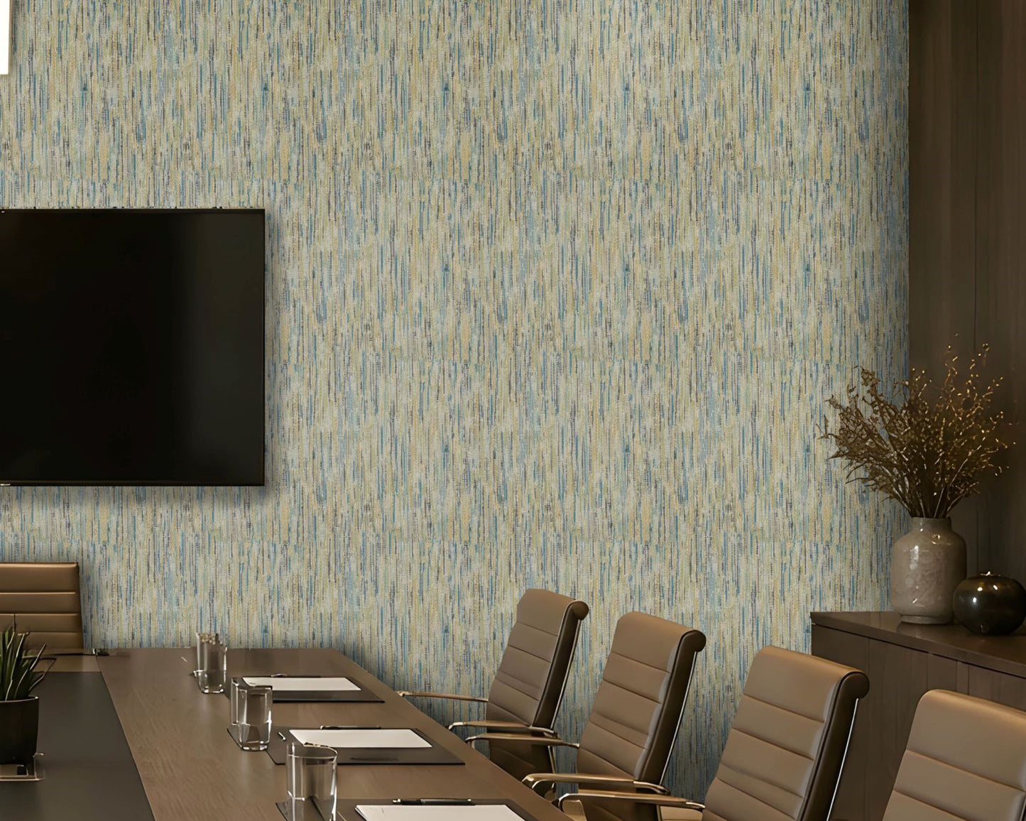 A modern conference room featuring a wall covered in vertical textured wallpaper with a blue and beige brushstroke pattern. A long wooden conference table, beige leather chairs, a wall-mounted flat-screen TV, and a sideboard with a vase of branches are visible.