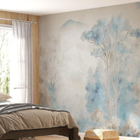 Misty blue ash watercolor forest mural wallpaper installed as a feature wall in living room, dining room, and bedroom interiors with soft blue and grey tones.