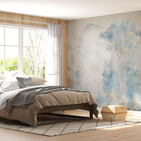 Misty blue ash watercolor forest mural wallpaper installed as a feature wall in living room, dining room, and bedroom interiors with soft blue and grey tones.