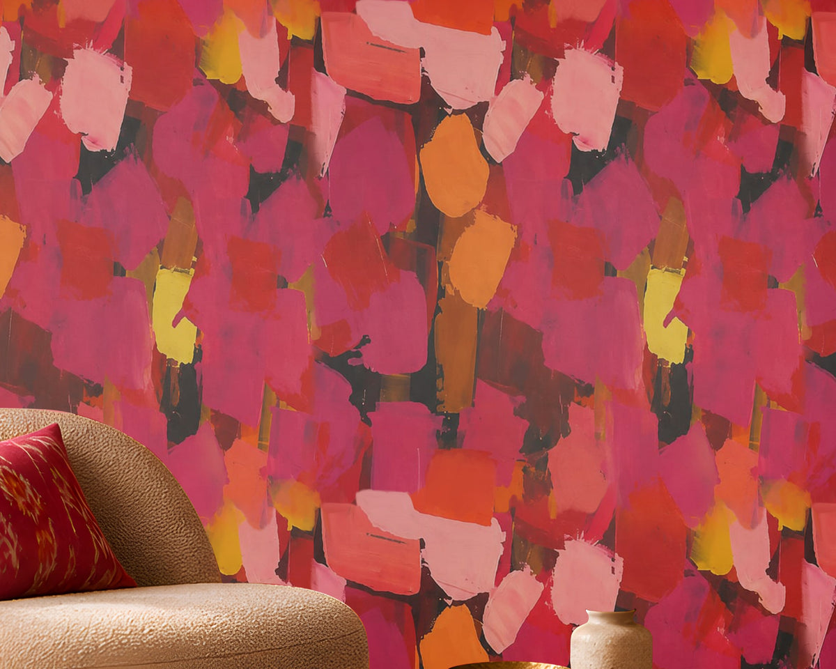 Modern Expression Coral Red abstract wallpaper featuring a bold, artistic brushstroke pattern in vibrant coral red, deep crimson, magenta, dusty pink, fiery orange, golden yellow, and charcoal accents. Displayed on a seamless statement wall in a contemporary living room, this expressive multicoloured wallpaper creates a warm, dramatic, and luxurious atmosphere. The interior features a cream boucle accent chair with a decorative red cushion, a round wooden coffee table, a dark wood fluted sideboard, a brass 